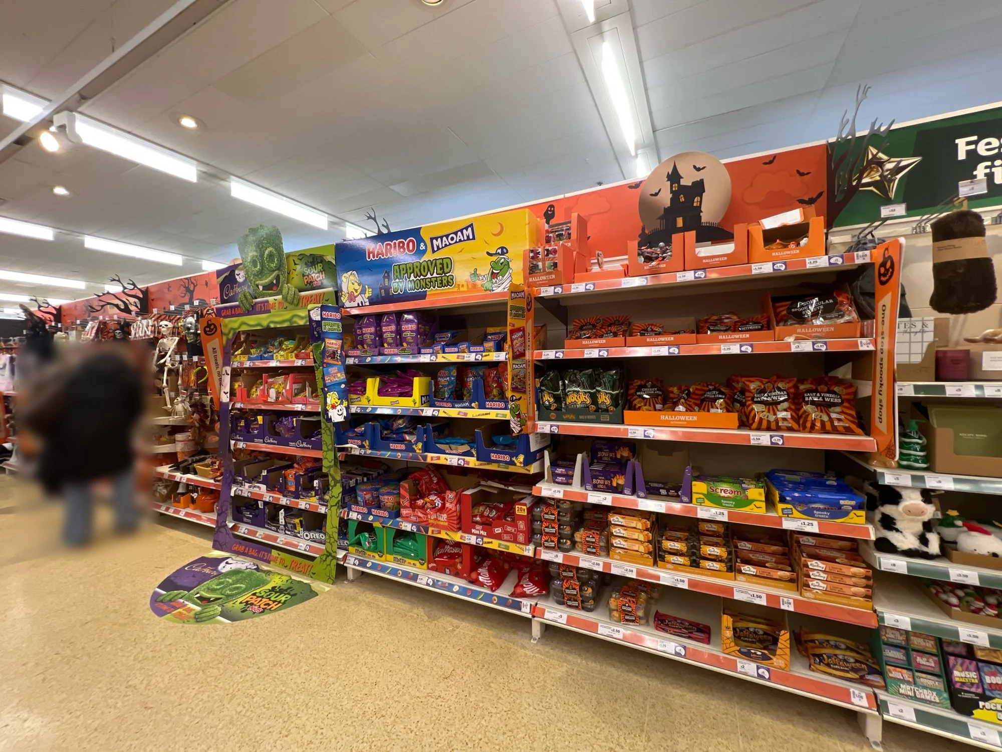 Halloween aisle in a UK supermarket with confectionery, savoury snacks and Halloween cakes